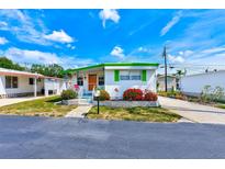 Charming single-story home with vibrant green trim and colorful flower bushes at 27466 Us Highway 19 N # 56, Clearwater, FL 33761