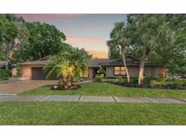 Charming single-story home with mature landscaping, brick driveway, and inviting curb appeal at sunset at 3320 Pattie Pl, Palm Harbor, FL 34685