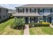 Inviting townhome featuring a covered porch, manicured lawn, and brick walkway at 4639 Bexley Village Dr, Land O Lakes, FL 34638