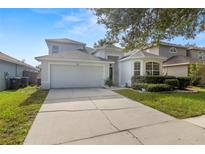 Charming two-story home featuring a two-car garage, a well-manicured lawn, and mature landscaping at 9818 White Barn Way, Riverview, FL 33569
