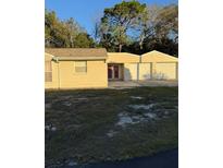 Tan house with red double doors and large two-car garage at 9900 Ideal Ln, Hudson, FL 34667