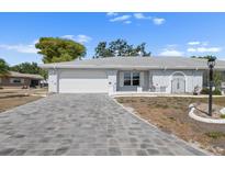 Charming single-story home with a gray brick driveway and manicured landscaping under a bright blue sky at 1002 Strawpocket Pl, Sun City Center, FL 33573