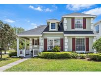 Charming two-story home with lush landscaping, covered porch, and red window shutters at 20053 Heritage Point Dr, Tampa, FL 33647