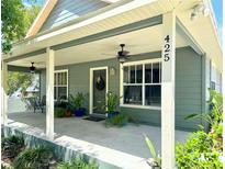 Charming home exterior featuring a spacious front porch with ceiling fans and lovely landscaping at 425 E Orange St, Tarpon Springs, FL 34689