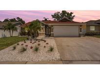 Charming single-story home with a well-maintained front yard, featuring white gravel, and palm trees at 4847 Harbor Woods Dr, Palm Harbor, FL 34683