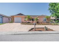 Charming single-story home featuring a brick driveway, lovely stone accents, and manicured landscaping at 7812 Turnbridge Dr, Port Richey, FL 34668
