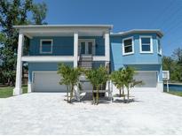 Two-story blue home with a white driveway, manicured landscaping, and two-car garages at 1033 Hammock Cir, Tarpon Springs, FL 34688