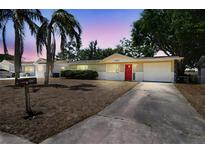 Charming single-story home featuring a red front door and well-maintained landscaping at 10817 Kingsbridge Rd, Port Richey, FL 34668