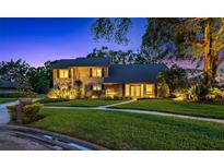 Charming two-story home featuring a lush, green lawn, mature trees, and well-lit exterior at 11804 Carrollwood Village Cv, Tampa, FL 33618