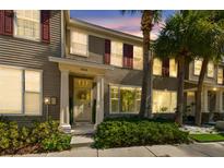 Charming townhome exterior featuring lush palm trees, red shutters, and a decorative front door at 12443 Country White Cir, Tampa, FL 33635