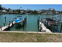 Waterfront property featuring boat dock with boat on lift, offering convenient access to the water at 12478 Capri Circle N # 2, Treasure Island, FL 33706