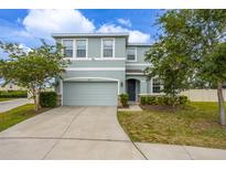 Two-story home with a two car garage, blue exterior paint, and well-maintained landscaping at 16633 Goose Ribbon Pl, Wimauma, FL 33598