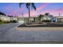 Charming single-story home featuring a screened porch and tropical landscaping with palm trees and cacti at 3349 Clydesdale Dr, Holiday, FL 34691