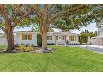 Charming single-story home features a well-manicured lawn, mature trees, and decorative shutters at 4920 17Th N Ave, St Petersburg, FL 33710