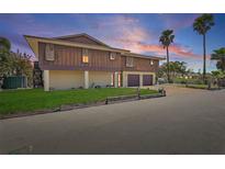 Two-story home with brown wood paneling, two-car garage, and well-maintained lawn under a colorful sky at 588 Bayview Dr, Longboat Key, FL 34228