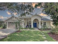 Charming home featuring a stucco exterior, well-manicured lawn, and a welcoming blue front door at 1069 Captains Way, Tarpon Springs, FL 34689