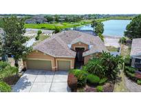 An aerial view of a home with a three-car garage, mature landscaping, and lake view at 11427 Laurel Brook Ct, Riverview, FL 33569