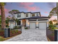 Beautiful two-story home with black framed windows, a three-car garage, and custom gray paved driveway at 1542 Bayshore Blvd, Dunedin, FL 34698