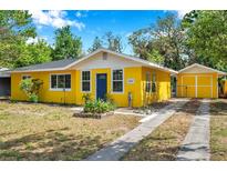 Charming yellow house with a blue door and well-maintained front yard at 1665 Laura St, Clearwater, FL 33755