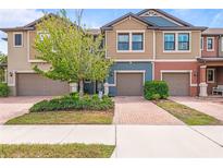 Charming townhome featuring colorful exteriors, manicured landscaping, and a paved driveway leading to attached garages at 16930 Red Brick Ln, Land O Lakes, FL 34638