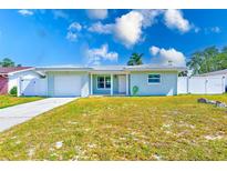 Charming single-story home featuring a well-maintained lawn, attached garage, and white fencing at 1859 Northview Rd, Largo, FL 33770
