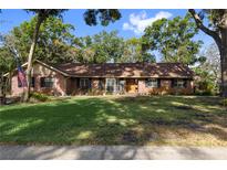 Charming single-story brick home featuring a well-manicured lawn and mature trees, creating a welcoming curb appeal at 2932 Chelsea Woods Dr, Valrico, FL 33596