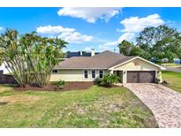 Charming single-story home featuring a lush front yard, brick driveway, and an attached garage, creating a welcoming curb appeal at 680 Capri Blvd, Treasure Island, FL 33706