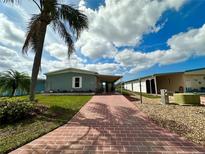 Charming single-story home with a brick driveway and a lush green lawn enhanced by a mature palm tree at 808 53Rd E Ave # 142K, Bradenton, FL 34203