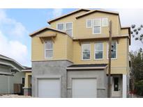 A newly constructed, two-story home with yellow siding and a two-car garage under blue skies at 1311 S Moody Ave # 1, Tampa, FL 33629