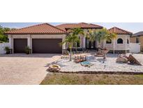 Charming home featuring a three-car garage, barrel tile roof, and ornate landscaping at 13878 Allamanda Cir, Port Charlotte, FL 33981