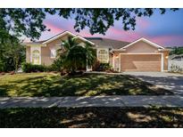 Charming single-story home with a well-manicured lawn, two-car garage, and beautiful landscaping at 1939 Heartland Cir, Valrico, FL 33594