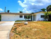 Charming one-story home with a manicured lawn, attached garage, and inviting front entrance at 2172 University S Dr, Clearwater, FL 33764