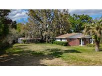 A single-story brick home with a spacious front yard and mature trees at 38327 Palm Grove Dr, Zephyrhills, FL 33542