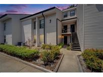 View of a two-story condo building featuring a landscaped yard with a cement walkway and black exterior stairs at 4709 Puritan Cir # 702, Tampa, FL 33617