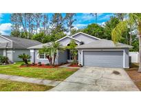 Charming single-story home featuring a well-manicured lawn, mature trees, and a two-car garage at 5143 New Brittany Ln, Zephyrhills, FL 33541