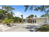 Charming single-story home featuring a well-manicured lawn and tropical landscaping with a light grey painted exterior at 8347 41St N Ave, St Petersburg, FL 33709