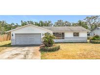 Single story home with a gray two car garage, desert landscaping, and palm tree at 8899 125Th St, Seminole, FL 33772