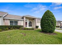 Charming single-story home featuring a well-manicured lawn, complemented by lush green bushes and a brick entryway at 1046 Almondwood Dr, Trinity, FL 34655
