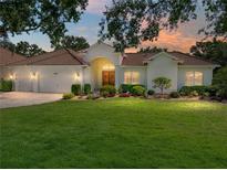Charming single-story home featuring a well-manicured lawn, lush landscaping, and a tile roof at 12902 Grand Traverse Dr, Dade City, FL 33525