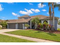 Charming two-story home featuring a three-car garage, manicured lawn, and lush landscaping at 12925 Tar Flower Dr, Tampa, FL 33626