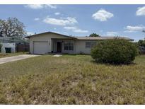 Exterior shot of a home with a garage and lawn in need of maintenance at 1905 Meridel Ave, Tampa, FL 33612