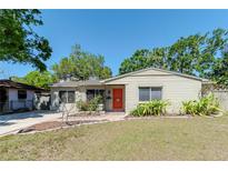 Charming single-story home featuring a well-maintained lawn and a vibrant, inviting front door at 4425 W Bay Villa Ave, Tampa, FL 33611