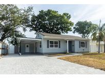 Charming single-story home with gray siding, gray shutters, covered parking, and a newly paved driveway at 551 84Th N Ave, St Petersburg, FL 33702