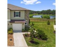 Beautiful two-story townhouse with a well-maintained front lawn, and a view of the lake at 7018 Ripple Pond Loop, Zephyrhills, FL 33541