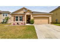 Tan single-Gathering home with a well-manicured lawn and attached two-car garage at 13312 Waterford Castle Dr, Dade City, FL 33525