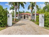 Stunning exterior of home with a tile roof, arched entryway, and palm tree lined paver driveway at 17347 Linda Vista Cir, Lutz, FL 33548