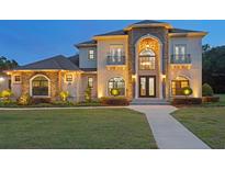 Stunning two-story home featuring a stone facade, arched entryway, and manicured landscaping at 18202 Bledsoe Loop, Lithia, FL 33547