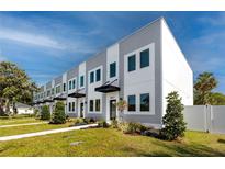 Modern townhomes feature gray and white exteriors, manicured lawns, and covered entryways, set under a bright sky at 3402 E 28Th Ave # 6, Tampa, FL 33605