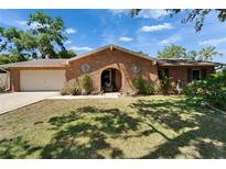 Charming brick home features an arched doorway, mature landscaping and a two-car garage at 402 Merlin Ct, Brandon, FL 33510