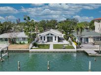 Charming waterfront home featuring a manicured lawn, waterfront access, and an inviting exterior at 8635 Boca Ciega Dr, St Pete Beach, FL 33706